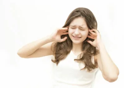 Woman plugging her ears in pain.
