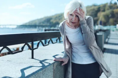 Older woman dizzy leaning on railing