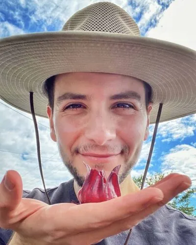 Adam Lindo wearing a hat with a flower in his hand.