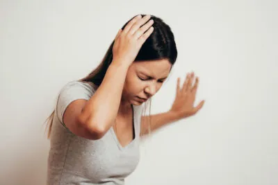 woman with her hand on her head and hand against the wall