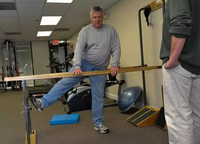 Man holding onto a support with one leg up.